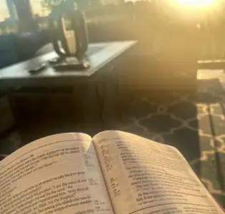 Open Bible illuminated by warm golden sunlight during a quiet moment of Bible reading.